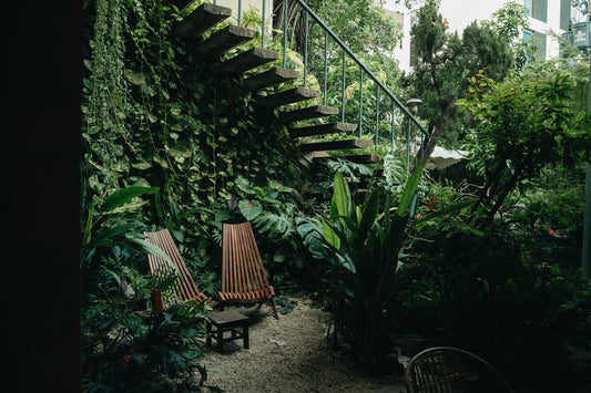 a couple of wooden chairs sitting next to a lush green wall